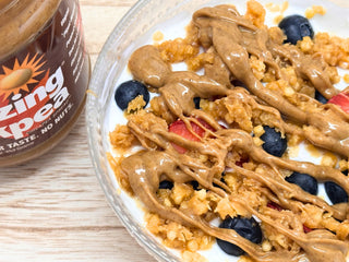 Close-up of yogurt with berries, granola, and drizzled chickpea butter beside a jar labeled 'The Amazing Chickpea'