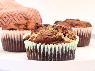 Three chocolate chip banana muffins on a white plate with a red towel behind